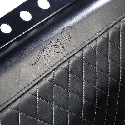 A close-up view of the embossed TATSoul logo on the seat back of the Comfort Before Pain Waiting Room Bench in black vinyl. 