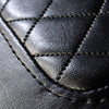 A close-up view of the diamond cushion stitching on the black vinyl seat of the Comfort Before Pain Waiting Room Bench by TATSoul.  